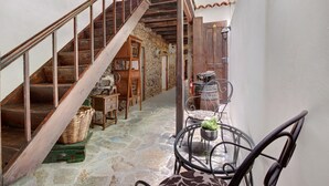 Eine Treppe führt zu einem Raum mit Steinboden, Holzmöbeln und einem Tisch mit einer Topfpflanze.