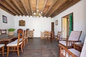 Un coin repas avec des meubles en bois, un lustre et une porte verte.