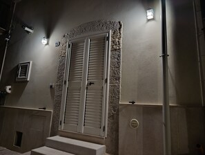 Ein Gebäudeeingang mit Doppeltüren, einem kleinen Fenster und einer Wandleuchte.