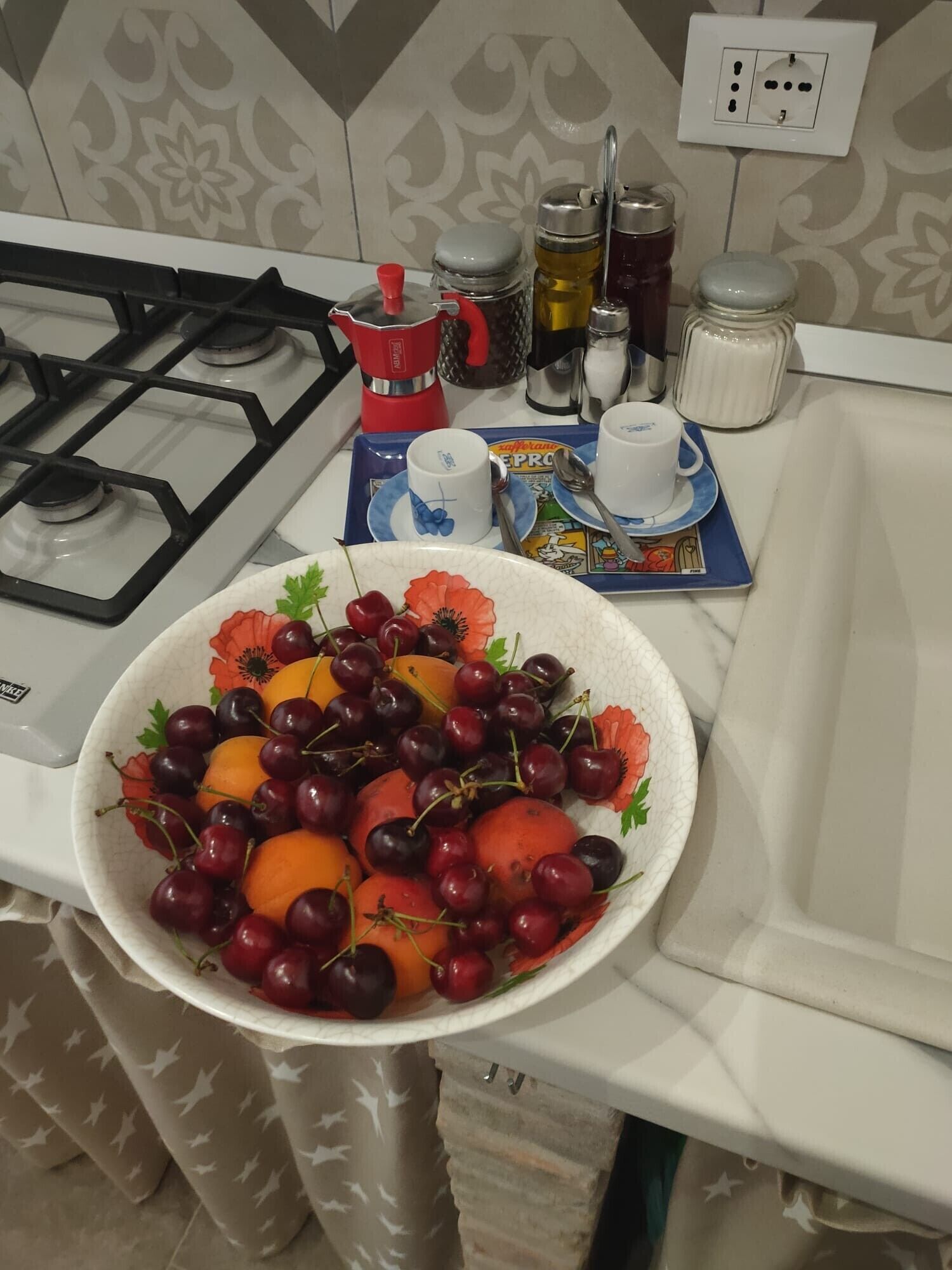 A kitchen counter with a bowl of fruit, a coffee maker, and various kitchen items.