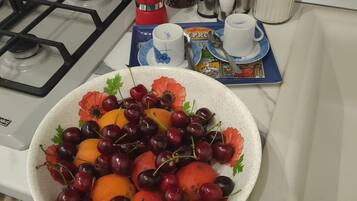 A kitchen counter with a bowl of fruit, a coffee maker, and various kitchen items.