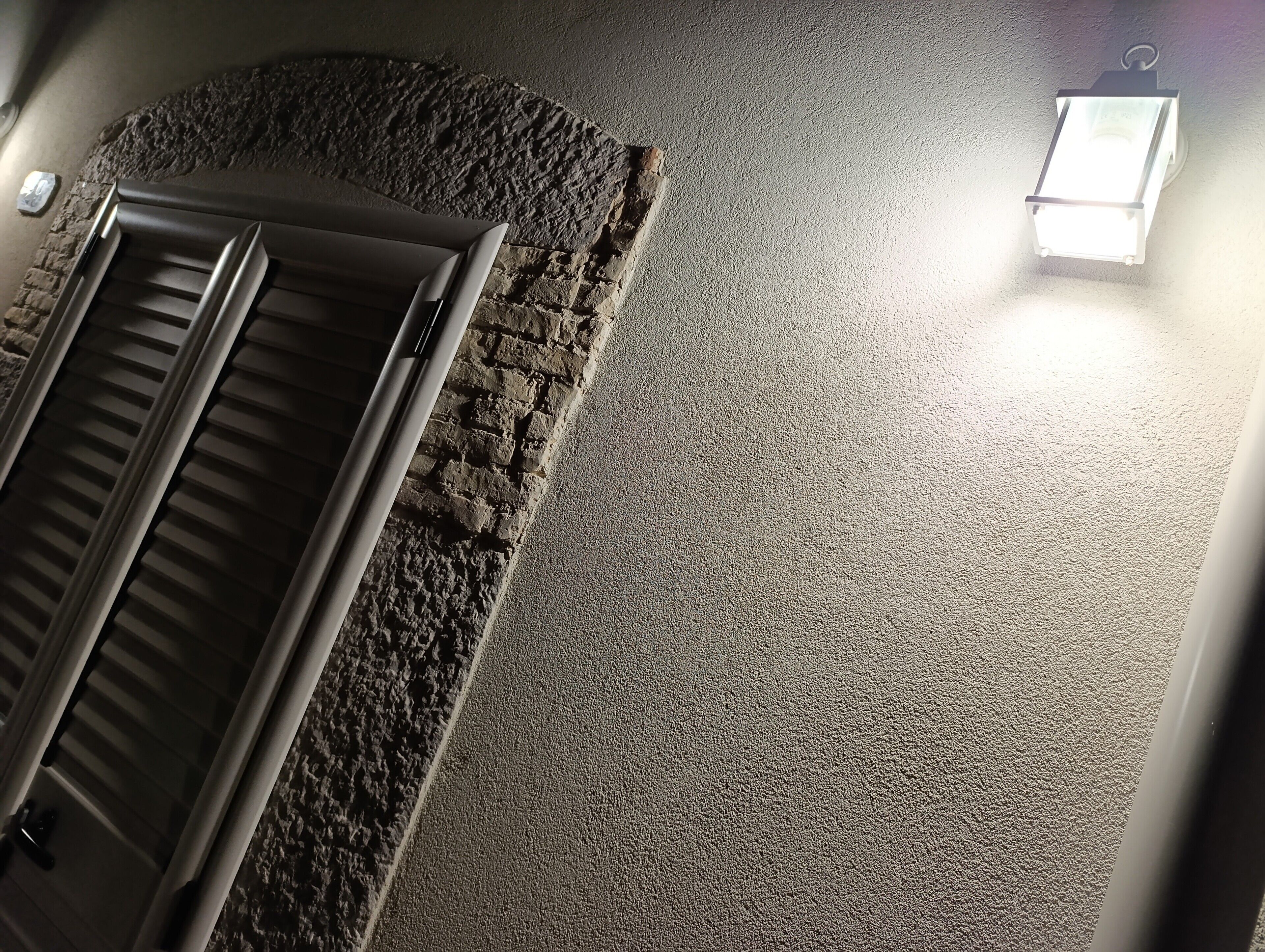 A room with a textured wall, a door, and a light fixture.