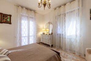 A bedroom with a bed, a dresser, a mirror, and a chandelier.