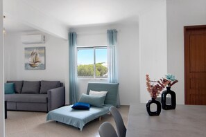 Een moderne woonkamer met een bank, een klein bed, een eettafel en twee vazen.