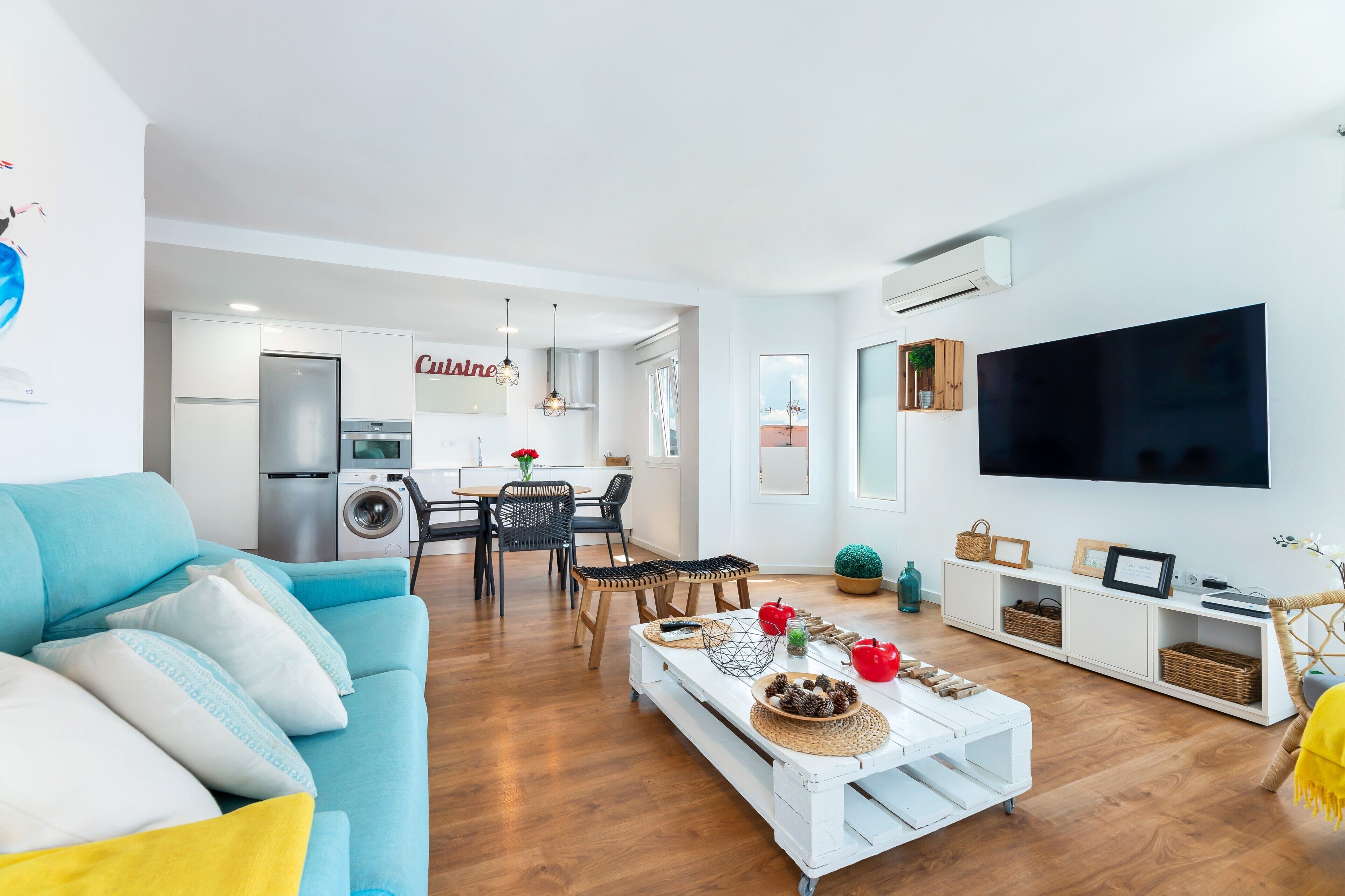 Una sala de estar moderna con sofá, mesa de centro, televisor y un comedor con sillas y una mesa.