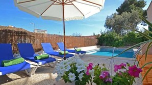 A poolside area with lounge chairs, a white umbrella, and potted flowers. - Villa 'Benestar' with Private Pool, Wi-Fi, and Air Conditioning (El Toro)