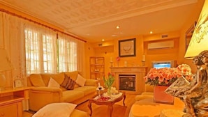 A living room with a sofa, a coffee table, a fireplace, and a statue. - Villa 'Benestar' with Private Pool, Wi-Fi, and Air Conditioning (El Toro)