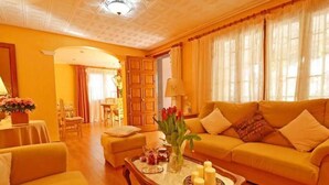 A living room with a sofa, armchairs, a coffee table with candles, and a dining area in the background. - Villa 'Benestar' with Private Pool, Wi-Fi, and Air Conditioning (El Toro)