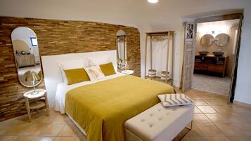 Quarto com uma cama grande, cabeceira de madeira, duas mesas de cabeceira, um espelho e um guarda-roupa.