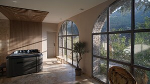 Un cuarto de spa con un jacuzzi, ventanas arqueadas grandes y vista al exterior.