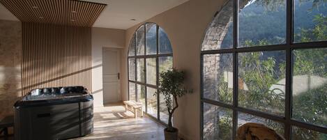 Un cuarto de spa con un jacuzzi, ventanas arqueadas grandes y vista al exterior.