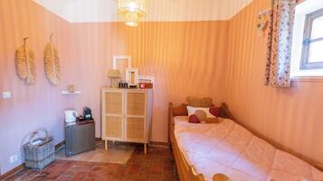 A bedroom with a bed, a chest of drawers, a wicker basket, and a ceiling light fixture.