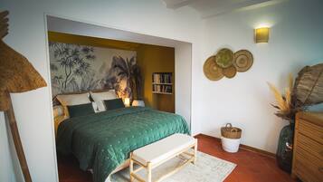 Een slaapkamer met een bed, een bankje, een boekenkast en decoratieve wandkunst.
