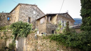 Un edificio de piedra con balcón, plantas en macetas y una puerta de madera.