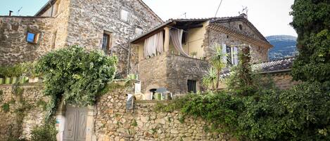 Un edificio de piedra con balcón, plantas en macetas y una puerta de madera.