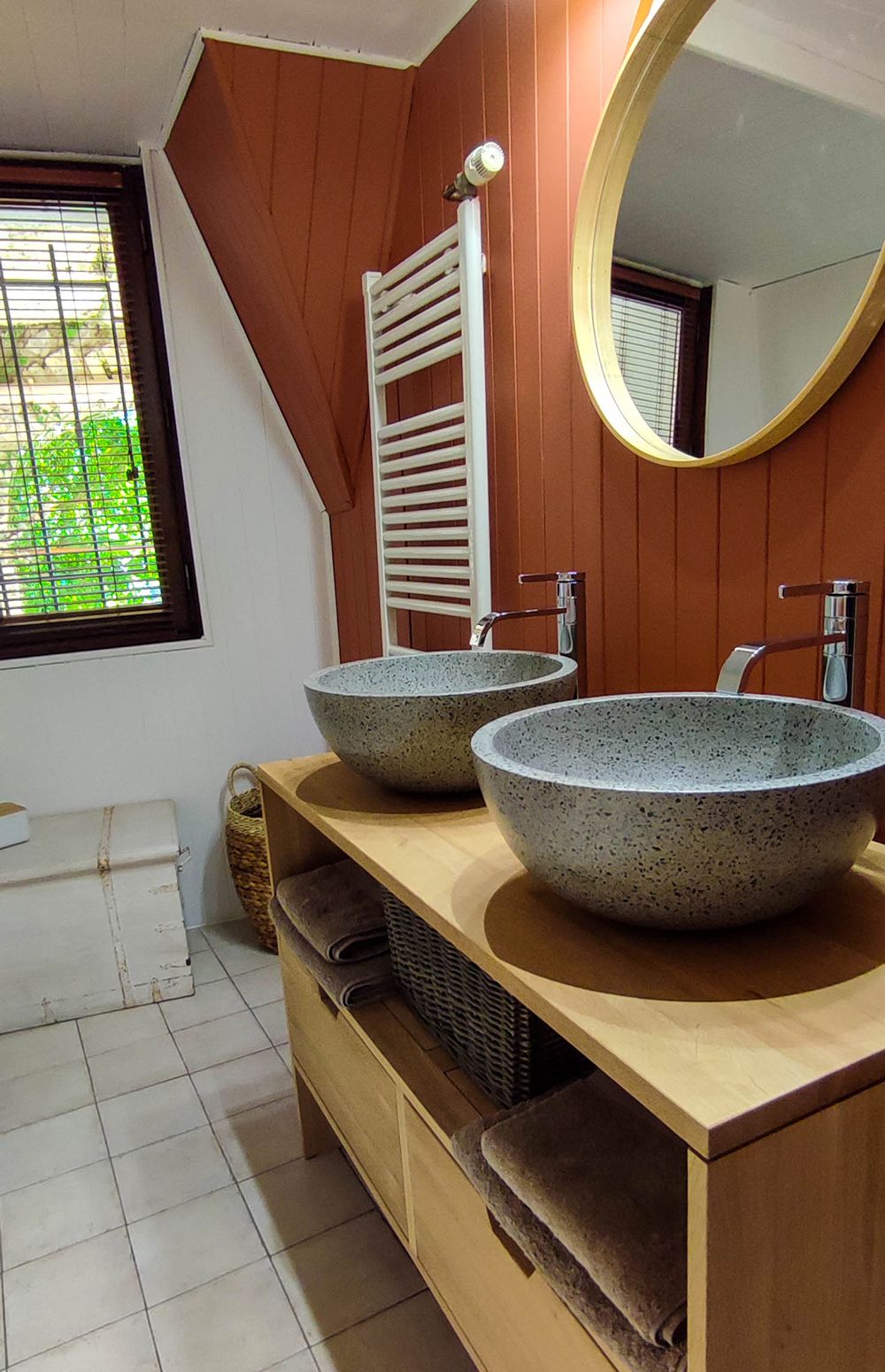 A bathroom with two large, speckled stone sinks, a wooden vanity, a towel rack, and a mirror.