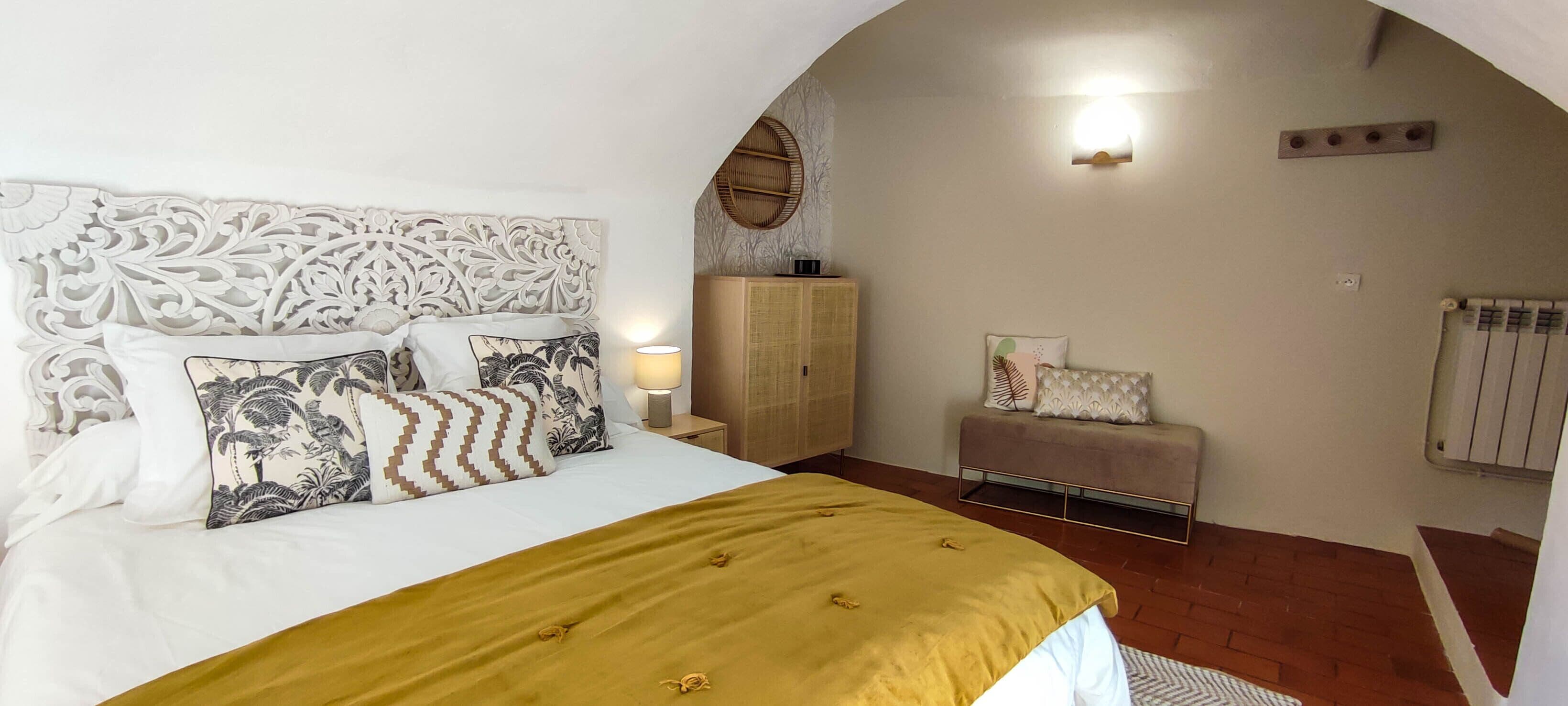 Ein Schlafzimmer mit Bett, Nachttisch, Kleiderschrank und einer Bank.