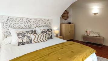 Een slaapkamer met een bed, nachtkastje, kledingkast en een bankje.