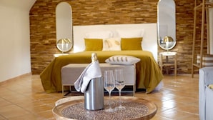 Un dormitorio moderno con cama, una mesita de noche con una botella y vasos, y un revistero decorativo.