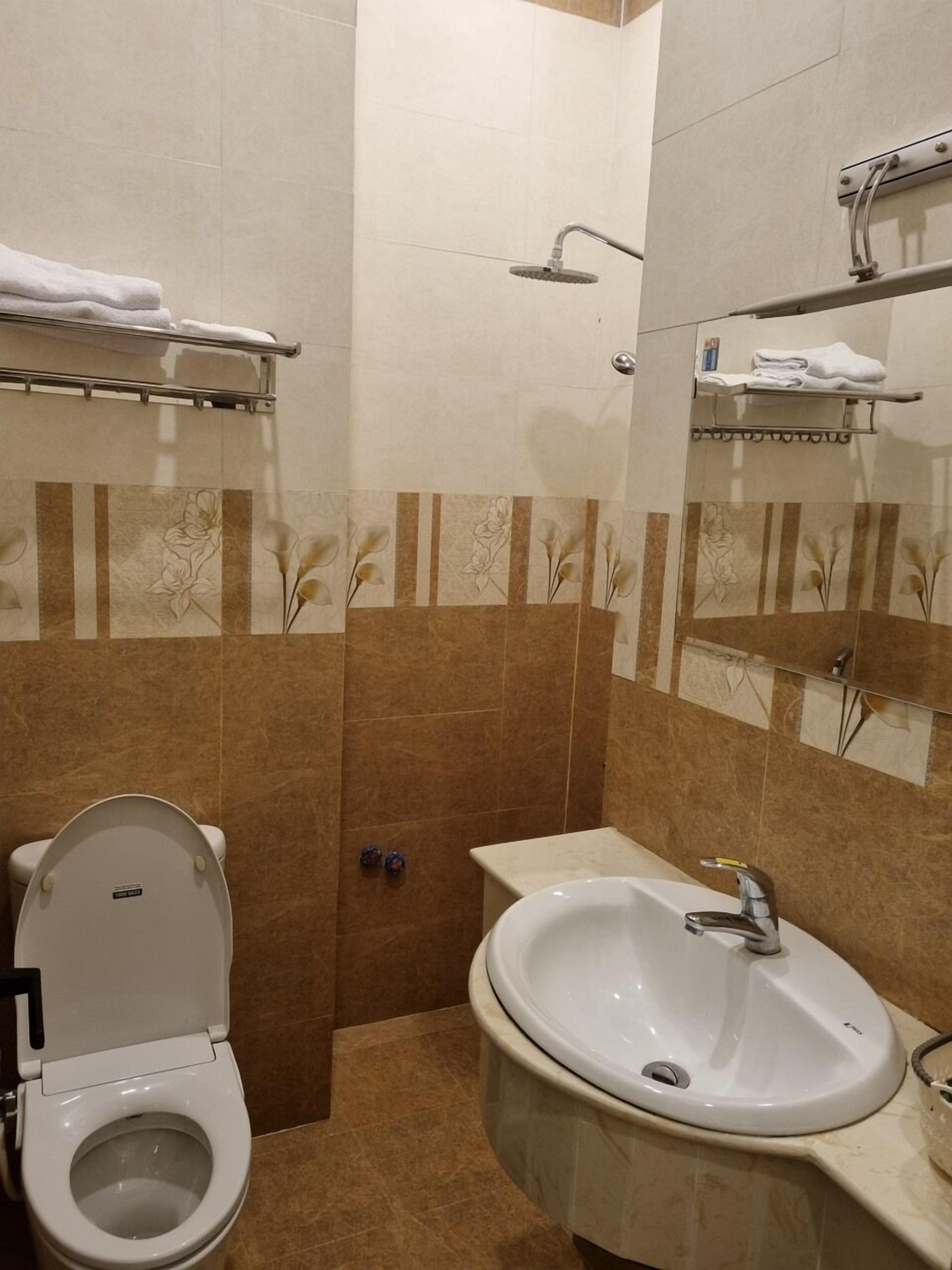 Ein Badezimmer mit Toilette, Waschbecken und Handtuchhaltern.