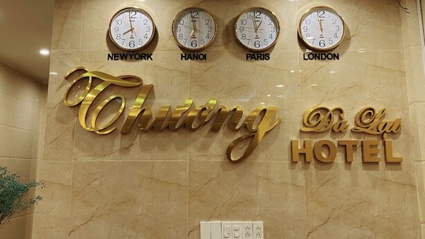 Un cartel de hotel con relojes que muestran las horas de Nueva York, Hanoi, París y Londres.