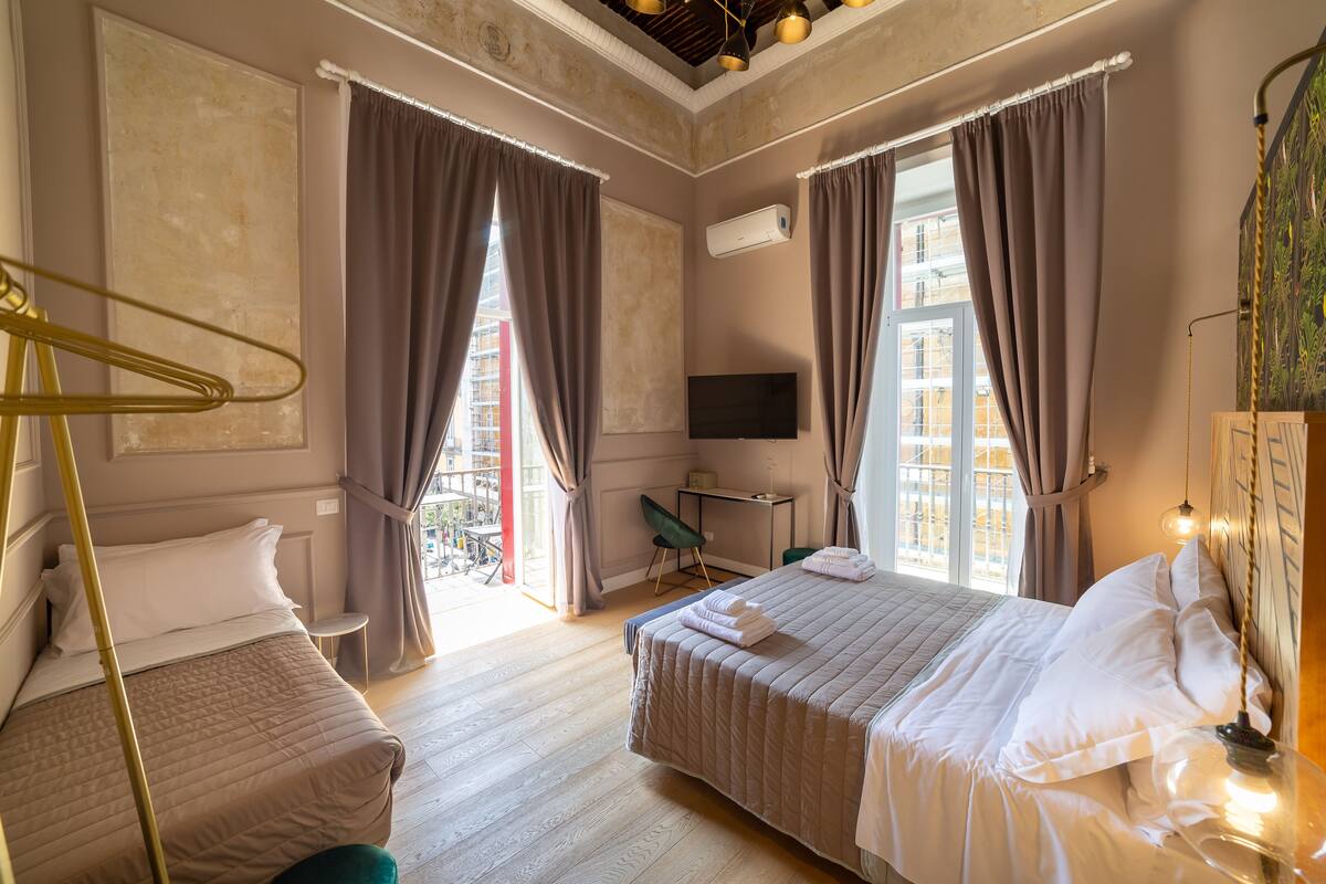 Une chambre d’hôtel avec deux lits, un bureau, une chaise et une télévision.