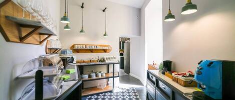 A modern kitchen with a black and white tiled floor, hanging green pendant lights, and a blue coffee machine.