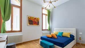 A bedroom with a bed, a radiator, a window with curtains, a painting on the wall, and a wooden floor. - Rialto Bridge Lovely Apartment (Venice)