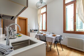 Une cuisine moderne équipée d’un évier, d’une cuisinière et d’un coin repas avec une table dressée pour quatre personnes.