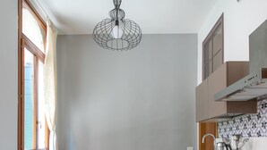 A modern kitchen with a dining table set for four, a gas stove, and a hanging light fixture. - Rialto Bridge Lovely Apartment (Venice)