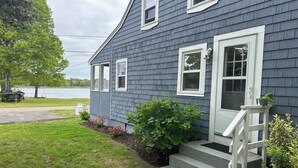 A house with a grey exterior, white trim, and a small porch with steps leading to the door.