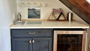 A kitchen with a built-in oven, a wine cooler, and a shelf with wine glasses.