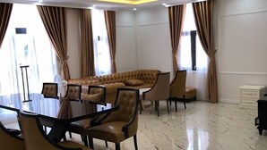 A spacious room with a large, round, tufted sofa, a dining table with chairs, and a chandelier. - Golden Sea Hotel (Bai Chay)