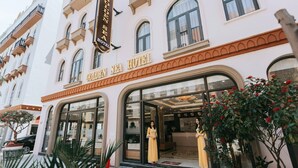 The exterior of the Golden Sea Hotel with a classic architectural style, large glass entrance, and potted plants in the foreground. - Golden Sea Hotel (Bai Chay)