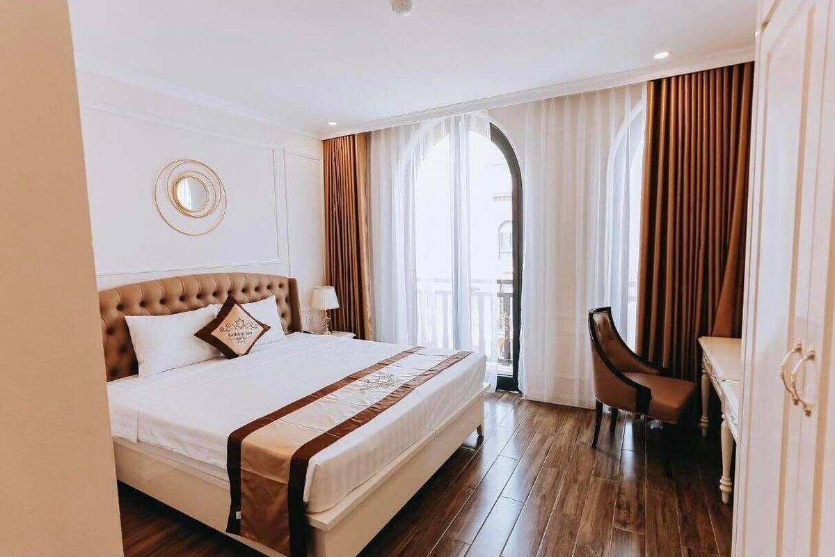 A hotel room with a large bed, a desk, and a chair.