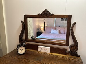 A wooden-framed mirror with a clock and a card on a wooden table.