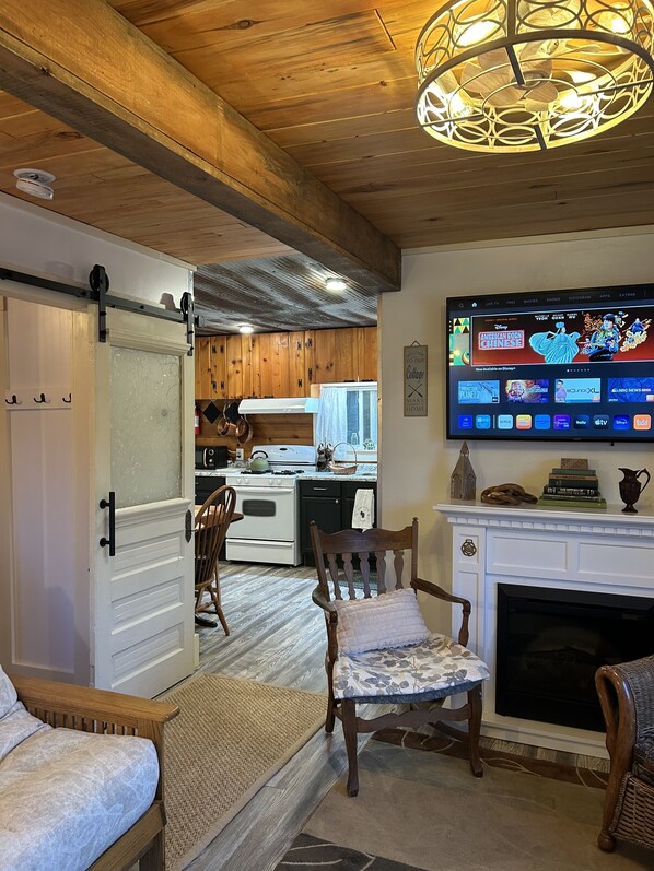 A cozy living room with a fireplace, a television mounted on the wall, and wooden flooring.