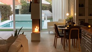 Ein modernes Wohnzimmer mit Kamin, Essbereich und Blick auf einen Swimmingpool.