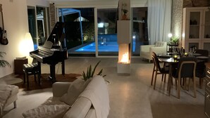 Ein modernes Wohnzimmer mit Klavier, einer Couch und einem Essbereich mit Stühlen und einem Tisch.