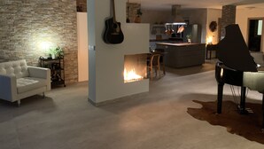 Ein modernes Wohnzimmer mit Kamin, einem Essbereich und einer Küche im Hintergrund.