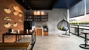 A modern kitchen with a brick wall, wooden shelves, and a hanging chair. - Cove W Suites (Jakarta)