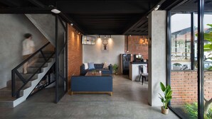 A modern interior with a staircase, a sofa, a coffee table, and a kitchen area. - Cove W Suites (Jakarta)