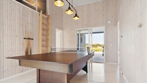 Una mesa de ping pong en una habitación con paredes de madera y vistas al exterior.