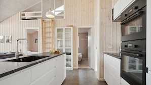 Una cocina moderna con una isla central, electrodomésticos integrados y detalles de madera.