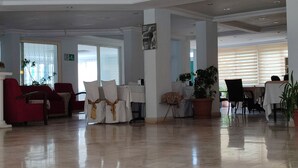 Un hall d’entrée spacieux, doté d’un sol ciré, de sièges rouges et blancs, et de grandes fenêtres.