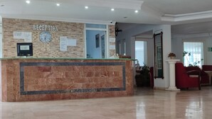 Un espace d’accueil doté d’un comptoir en marbre, d’une horloge et de panneaux d’information.