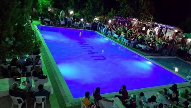 Une piscine extérieure entourée d’une foule de personnes.