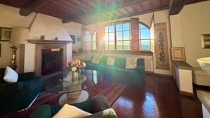 A cozy living room with a fireplace, a glass coffee table, and a view of the outdoors. - VILLA GIOTTO, FLORENCE (Impruneta)