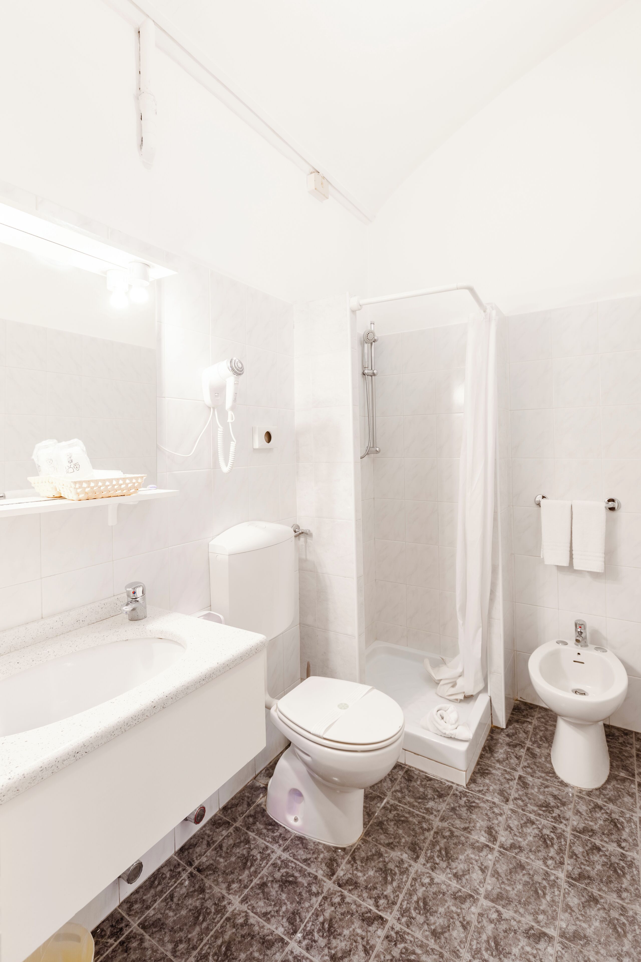 A modern bathroom with a bathtub, toilet, bidet, and a shower enclosure.