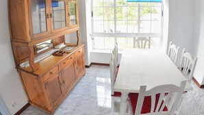 Un comedor con un mueble de madera, una mesa blanca y sillas.